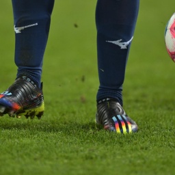 Szene aus dem Fußball-Bundesligaspiel FC Augsburg - VfL Bochum mit Regenbogenfarben auf dem Schuh eines Bochumer Spieler und auf dem Spielball

