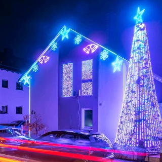 In Karlsruhe leuchtet ein Haus, das mit rund 90 000 LED-Lichtpunkten weihnachtlich geschmückt ist. Im Vordergrund fährt ein Auto vorbei.