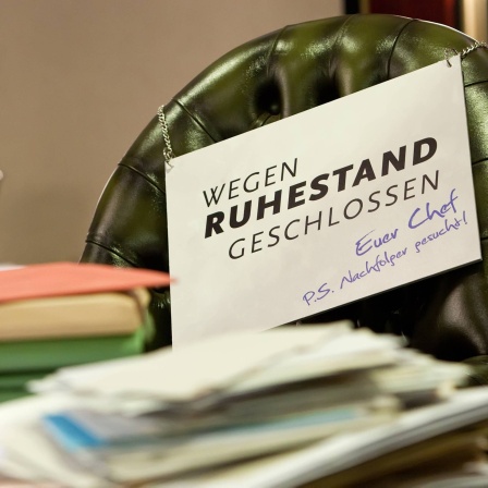 Symbolbild mit vollem Schreibtisch und Schild &#034;Wegen Ruhestand geschlossen&#034;