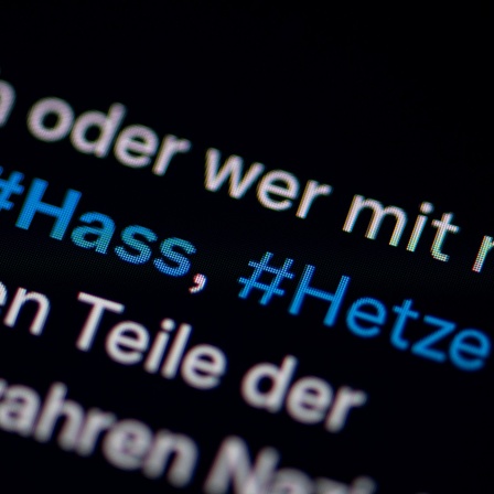 Auf dem Bildschirm eines Smartphones sieht man die Hashtags Hass und Hetze in einem Twitter-Post 