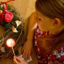 Kind zündet Kerze auf einem Adventskranz an