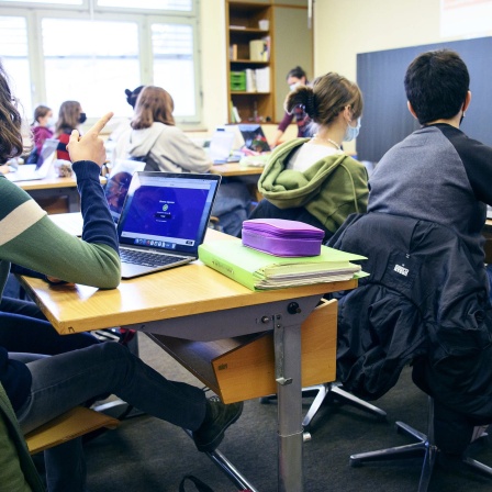 Schüler sitzen mit Laptop in der Schule
