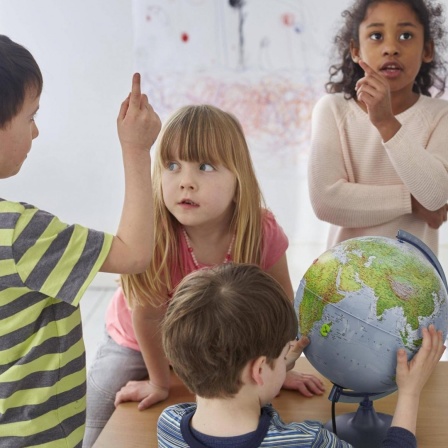 Diskutierende Kinder um einen Tisch, mit einem Globus.