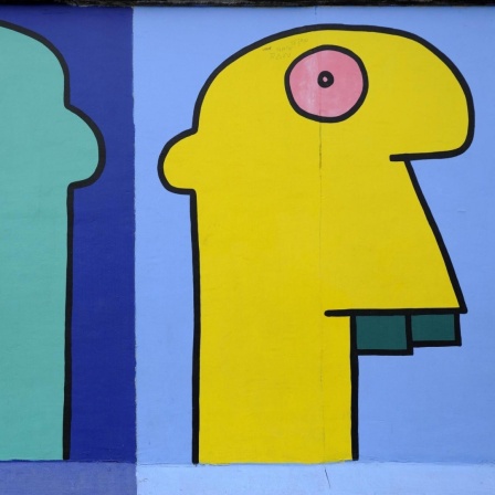 Mauer-Gemälde des Künstlers Thierry Noir. Es zeigt bunte Köpfe im Comicstil auf der Berliner Mauer, East Side Gallery, Berlin.