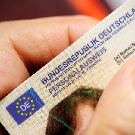 Eine Frau hält einen Personalausweis der Bundesrepublik Deutschland im Scheckkartenformat in ihrer Hand.