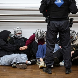 Polizisten stehen während der Besetzung des Audimax der Universität Leipzig um fünf junge Menschen. 