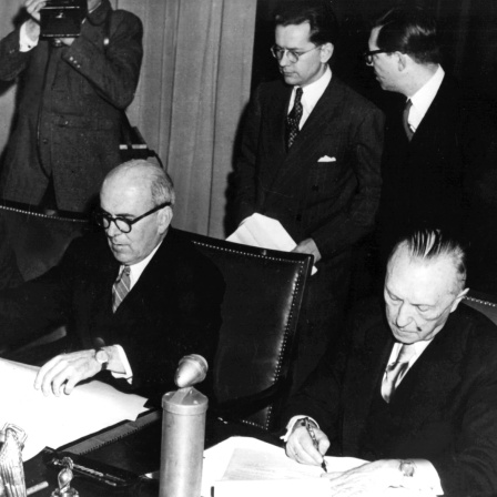 Der Direktor der Abteilung für Wirtschaftsangelegenheiten bei HICOG, R. M. Hanes, Hochkommissar John McCloy und Bundeskanzler Konrad Adenauer (v.l.n.r.) Am 15. Dezember 1949 unterzeichneten McCloy und Adanauer das zweiseitige Abkommen über die amerikanische Wiederaufbauhilfe für Europa, den Marshallplan genannten ERP-Vertrag. Es ist der erste von der Bundesrepublik Deutschland geschlossene internationale Vertrag.