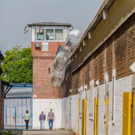 Das Beitragsbild des Dok5 "Ersatzfreiheitsstrafe - Streit um den Schuldturm für Arme" zeigt zwei Gefängnisinsassen auf dem Anstaltsgelände der Justizvollzugsanstalt Werl.