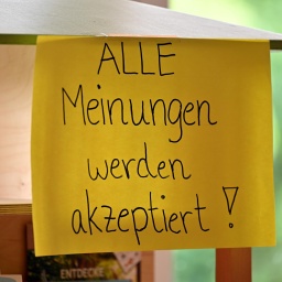 Auf einem befestigten, hängenden Blatt Papier steht: "Alle Meinungen werden akzeptiert".