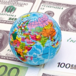 Ein Globus liegt auf Dollar- und Euroscheinen (Symbolbild).