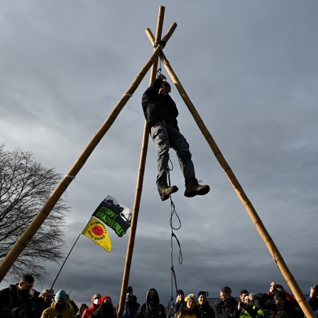 Ein Klimaschutzaktivist hängt während des Aktionstrainings an einem Tripod um die bevorstehende Räumung durch die Polizei zu proben