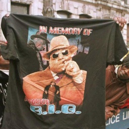 Fans entlang einer Absperrung; Ein Mann hält ein T-Shirt mit der Aufschrift "In memory of Notorius B.I.G." und dessen Gesischt hoch.