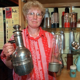 Aus dem Museum in der ehemaligen Schleiferei für Glasprodukte in der Gemeinde Glashütte bei Baruth zeigt eine Mitarbeiterin historische Thermoskannen