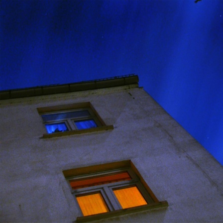 Eine Hausecke mit beleuchteten Fenstern in der Nacht