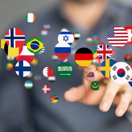 Runde Buttons mit Nationalflaggen schweben in der Luft und werden mit dem Finger angetippt: Insgesamt gibt es auf der Welt ungefähr 7.000 Sprachen. Die Sprachenvielfalt konzentriert sich insbesondere um den Äquator herum.