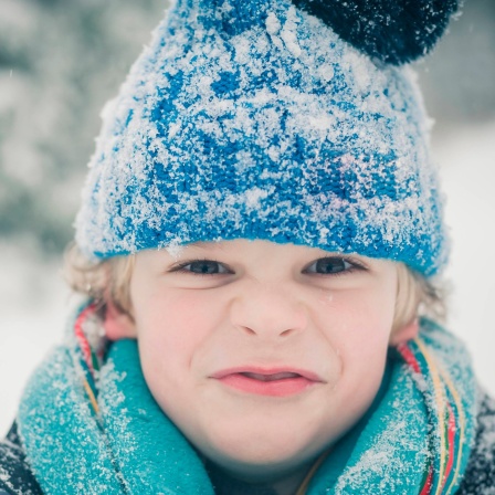Ein Junge mit Mütze und Schal im Schnee