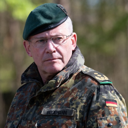 André Bodemann, Generalleutnant, steht in Camouflage-Uniform und Barett auf dem Truppenuebungsplatz in Munster