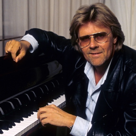 Der Schlagersänger und Komponist Howard Carpendale sitzt lässig an einem Klavier.