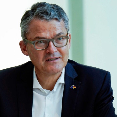 Der CDU-Politiker Roderich Kiesewetter sitzt auf einem Podium vor einem Mikrofon.