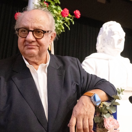 Der Stuttgarter Sterne-Koch und Autor Vincent Klink lehnt sich lässig mit dem Ellbogen auf ein blau verpacktes Geschenk