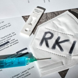 Symbolbild RKI-Protokolle zu Covid-19. Geschwärzte Dokumente mit FFP2-Maske und der Aufschrift RKI (Bild: picture alliance / CHROMORANGE | Michael Bihlmayer) 