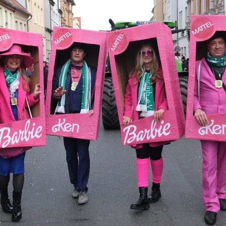 Karnevalsfreunde in Kostümen von Barbie und Ken gehen durch das Stadtzentrum. Nach zweijähriger Zwangspause wegen der Corona-Pandemie fand in Köthen wieder ein großer Faschingsumzug statt.