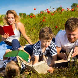 Eine Familie liest auf einer Wiese Bücher