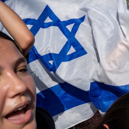 Israelis feiern mit israelischen Flaggen auf den Straßen nach der sicheren Rückkehr von vier israelischen Geiseln.