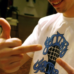 In einem T-Shirt mit dem Gitter Spitter Records-Logo posiert MC Eklat mit zwei Mittelfingern.