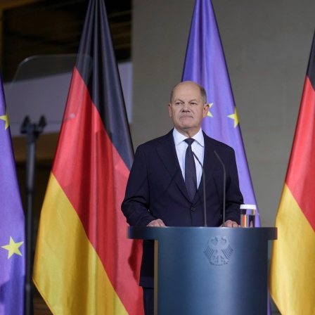 Bundeskanzler Scholz gibt ein Pressestatement vor dem Kanzleramt - er steht vor deutschen und europäischen Flaggen. 