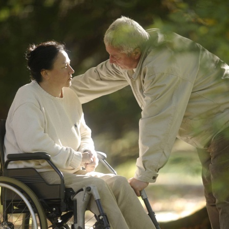 Symbolbild - Mann spricht mit seiner Frau im Rollstuhl