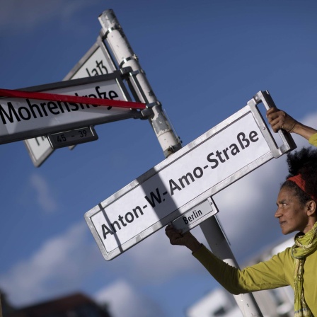 ARCHIV, Berlin, 23.08.2017: Frau protestiert mit Strassenschild "Anton-W.-Amo-Strasse" als neuen Namensgeber in Erinnerung an den ersten deutschen schwarzen Akademiker Anton Wolhelm Amo (Bild: IMAGO/IMAGO)