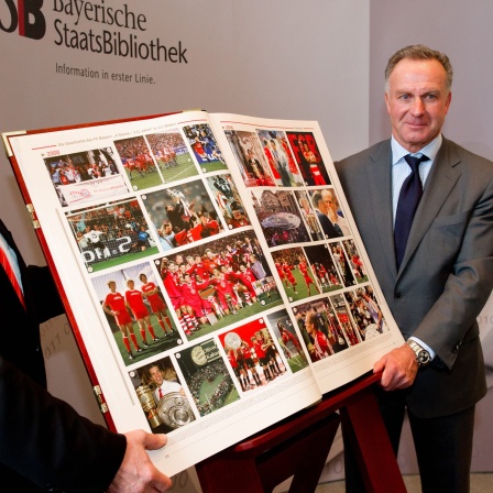 Karl-Heinz Rummenigge, übergibt die FC Bayern-Chronik an Rolf Griebel