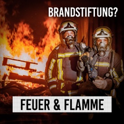Zwei Feuerwehrleute vor brennenden Paletten