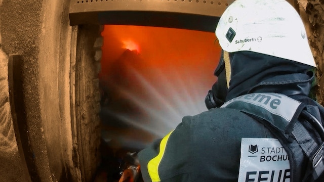 Ein Feuerwehrmann löscht einen Raum in einem leerstehenden Gebäude.