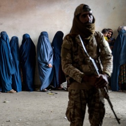 Ein Taliban-Kämpfer steht Wache, während Frauen darauf warten, Lebensmittelrationen zu erhalten, die von einer humanitären Hilfsorganisation in Kabul, Afghanistan, verteilt werden, Dienstag, 23. Mai 2023.