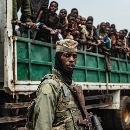 Ein M23-Kämpfer steht im Vordergrund, während inhaftierte FARDC-Soldaten auf Lastwagen verladen werden, um an einen unbekannten Ort gebracht zu werden, 30. Januar 2025.