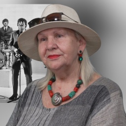 Rosi Sheridan mit einem historischen Foto der Beatles im Hintergrund.
