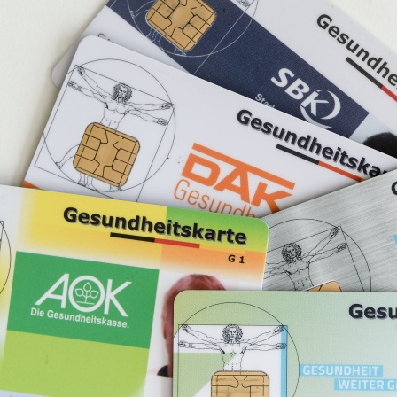 Gesundheitskarten verschiedener Krankenkassen liegen auf einem Tisch.