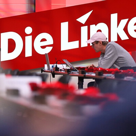 Ein DJ vor einem Banner von der Partei Die Linke