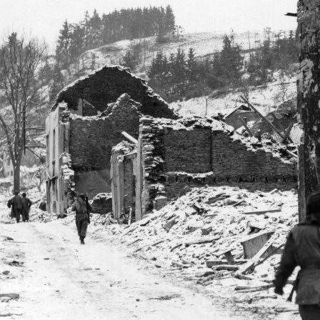 Soldaten auf den Straßen des verschneiten und zerbombten Houffalize, Belgien, im Januar 1945