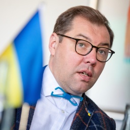 Oleksii Makeiev, Botschafter der Ukraine in Deutschland, bei einem Treffen. Im Vordergrund ist die ukrainische Fahne.