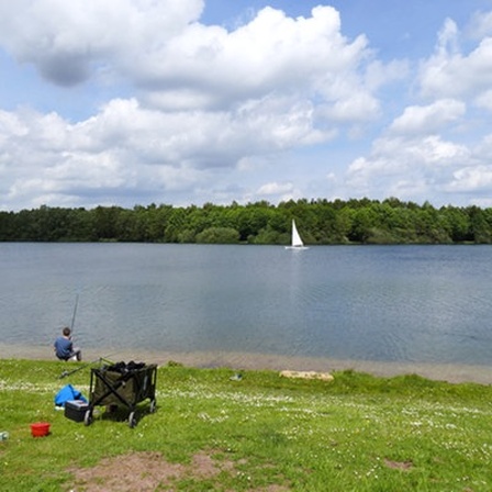 Ein Mann sitzt an einem See und angelt.