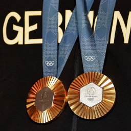 Olympia, Paris 2024, ein Athlet steht mit zwei Goldmedaillen im Deutschen Haus.