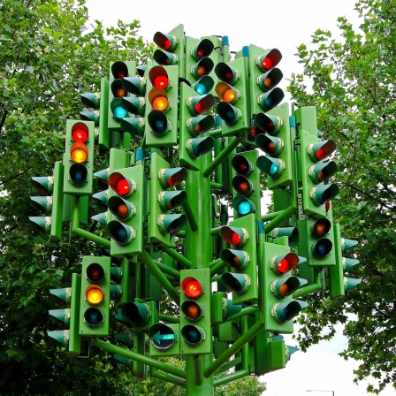 Ein Baum aus vielen leuchtenden Ampeln steht an einer Strassenecke.