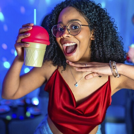 Partystimmung: Eine Frau lacht und hält ein Getränk in der Hand