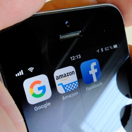 Die Logos der US-Internetkonzerne Google (l-r), Amazon und Facebook sind auf dem Display eines iPhone zu sehen.