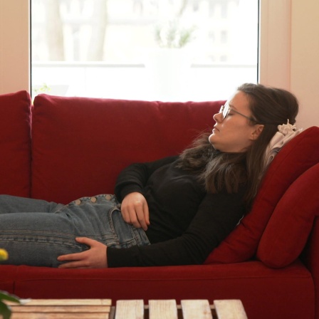 Eine junge Frau (Katharina Milde) liegt auf einem Sofa und schläft