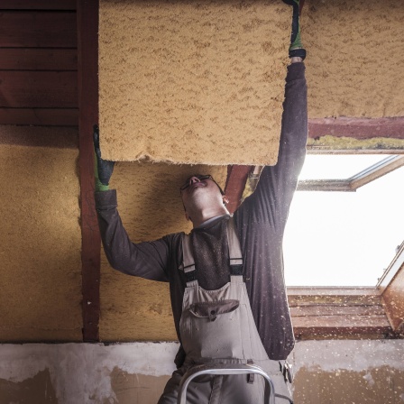 Ein Handwerker bringt Dämmplatten an.