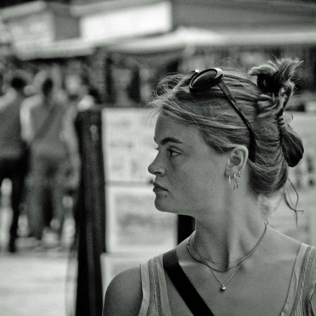 Eine junge Frau steht in einer vollen Passage und blickt nach links, schwarzweiß Aufnahme